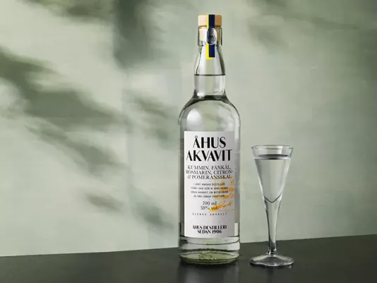 A bottle of clear aquavit on a wooden table