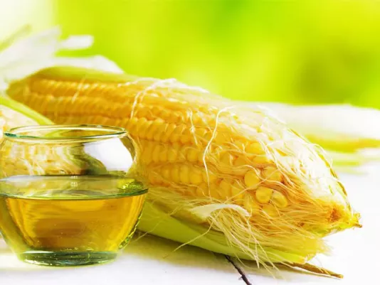 Кукурудзяна олія поруч із качанами кукурудзи