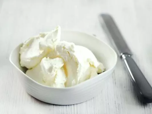 Cream cheese in a ceramic bowl with a spreading knife