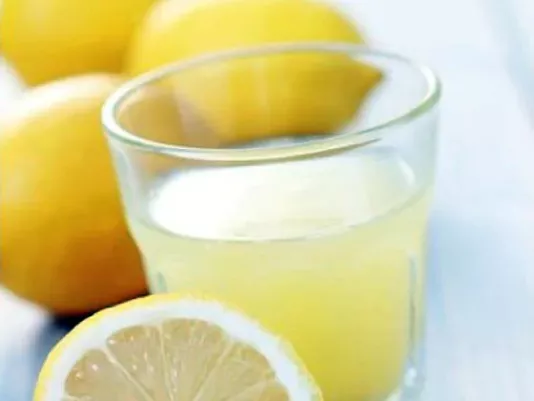 Freshly squeezed lemon juice in a glass next to a lemon