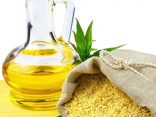 Sesame oil in a bottle and sesame seeds nearby