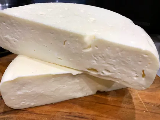 White semi-hard cheese in section with a delicate fibrous structure