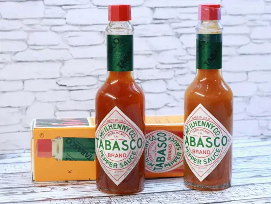 A bottle of red hot sauce on a kitchen table
