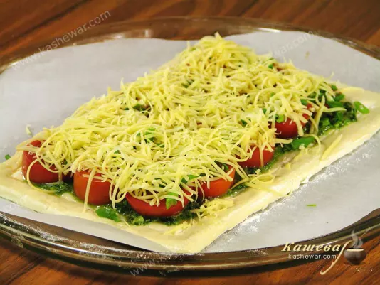 Baking a pie with tomatoes, pesto and cheese